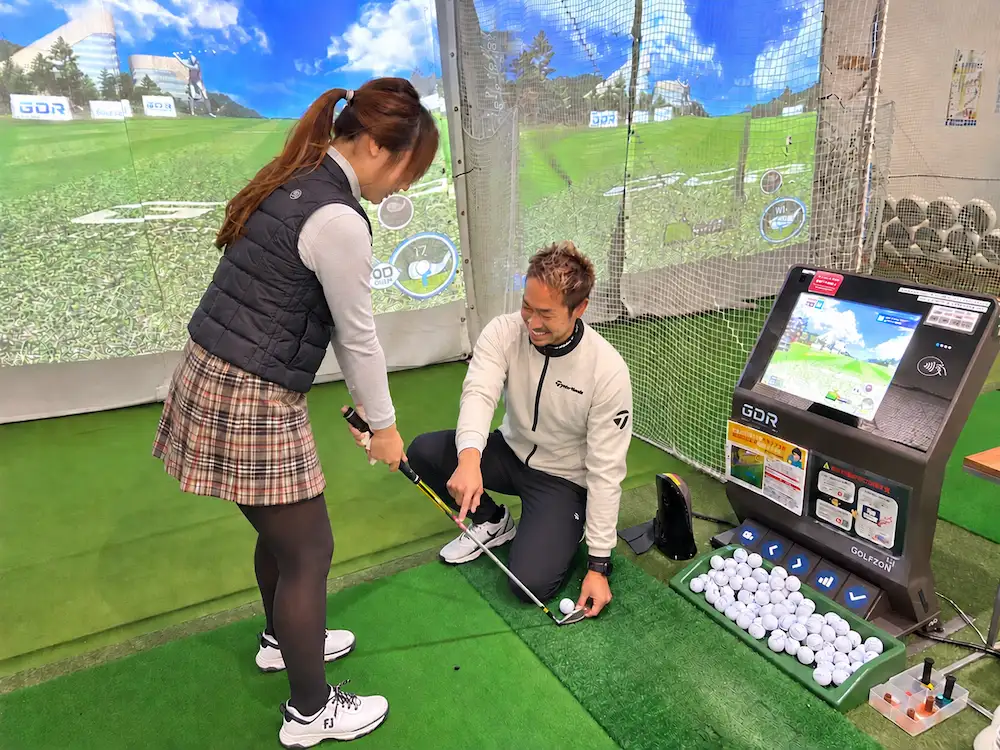 GDRの打席でコーチがしゃがんでアドレスを指導するレッスンの様子